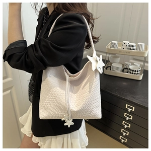Detail of white woven hobo bag with trendy star charms and braided shoulder strap