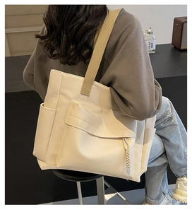 Detail view of the beige canvas tote bag with multi-pocket design and wide shoulder strap