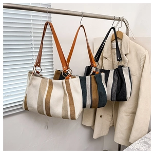 Detailed view of striped canvas tote bags in various colors hanging on a metal rack