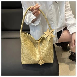 Close-up of woven tote bag with star charms on a leather strap and textured handle