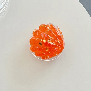 Detail showing shell-shaped phone grip with orange resin and gold foil flakes