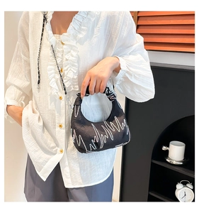 Detail of black pleated crescent bag with wave embroidery and woven shoulder strap