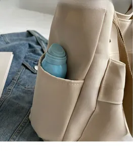Macro view of canvas tote side pocket showing functional storage and brown strap details