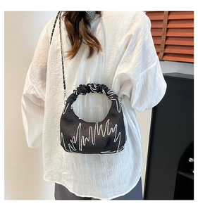 Detail of black crescent bag featuring wavy white stitching and pleated cloud handle