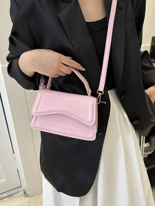 Pink shoulder bag with unique wavy flap design and gold hardware shown on a model outfit