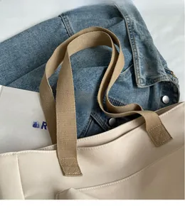 Close-up of smooth khaki shoulder strap and off-white canvas tote bag details