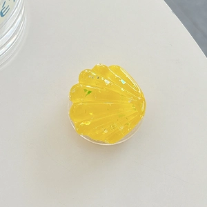 Macro shot of yellow shell-shaped resin phone grip with sparkling rainbow glitters