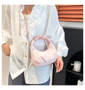 Detail of light pink quilted cloud bag featuring soft fabric texture and chain strap