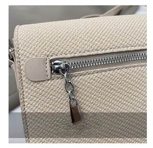 Detail shot of the smooth metal zipper and silver chain puller on the woven crossbody bag