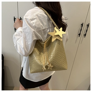 Detailed view of golden woven shoulder bag featuring unique star-shaped leather charms
