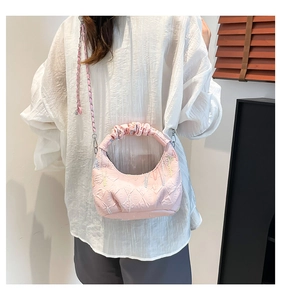 Detail of pink quilted hobo bag with contrast stitching and ruffled handle on a shoulder strap