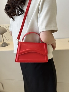 Detail of red structured crossbody bag with unique wave texture and golden hardware