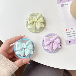 Three magnetic bow phone grip holders in pastel colors with clear circular bases