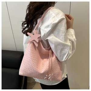 Detailed close-up of a pink woven hobo tote bag with star charms and textured shoulder strap