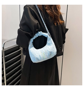 Detail of light blue crescent bag featuring pleated texture and chain strap worn on back