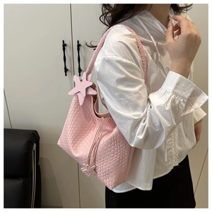 Detail of pink woven tote bag with star charms and drawstring in a lifestyle setting