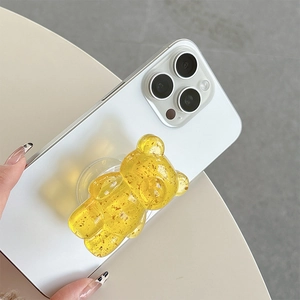 Detail showing transparent yellow gummy bear phone grip with gold foil on a white smartphone