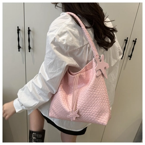 Detail view of pink woven leather tote bag featuring a star charm and braided shoulder strap
