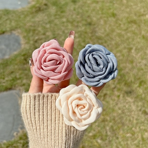 Detailed view of 3D fabric flower phone grips in pink, blue, and cream on a sunny lawn