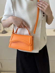 Detail of orange wave-patterned flap and golden hardware on fashionable crossbody bag