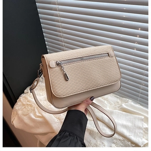 Detail of beige woven fabric texture and smooth leather finish on small square crossbody bag