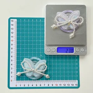 Detailed scale view of the bow-shaped butterfly phone grip with pearls and embroidery