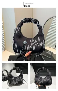 Detail of black cloud bag featuring colorful embroidery, ruched handle and silver chain