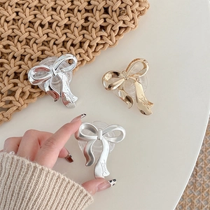 Detailed view of metallic bow phone grips in silver and gold finishes on a white surface