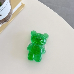 Macro shot of green transparent bear phone grip with gold foil inside on desktop