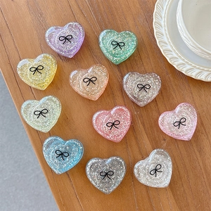 Close-up of heart-shaped glitter phone grips with bow pattern in 11 vibrant colors