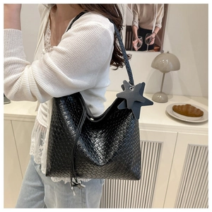 Detail of black woven leather tote bag featuring star charms and rope shoulder strap