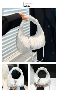 Detail of white half-moon bag with letter embossing, ruffled handle and silver chain