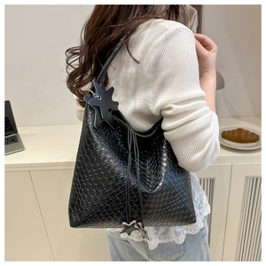 Detail of black woven tote bag with star pendant on model in a modern home setting