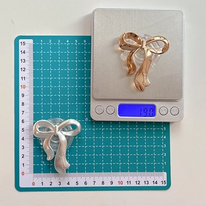 Detail showing metallic bow phone stand dimensions on scale and green grid mat