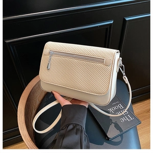 Detail of beige textured fabric and cream leather flap on chic crossbody square bag