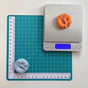 Detail of round button phone grip with bow tie, showing 14.0g weight on scale