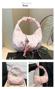 Detailed view of pink ruched handbag featuring a quilted moon shape and chain strap