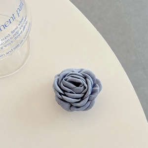 Close-up of blue fabric rose phone grip with layered textile petals and vintage texture