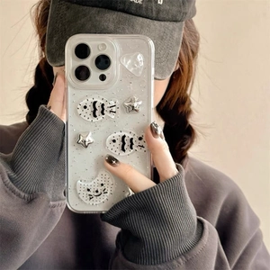 Detail of clear iPhone case with silver fish and star charms held by a model