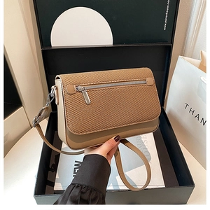 Detail of camel crossbody bag featuring woven texture flap and adjustable strap
