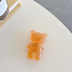Detailed macro view of amber resin bear phone grip with decorative gold foil flakes