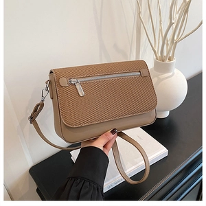 Detail of khaki crossbody bag with woven texture lid and silver zipper pocket