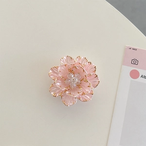 Macro detail of 3D pink floral phone grip with gold edges and crystal center embellishment