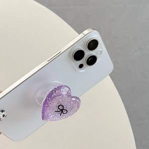 Detailed view of heart-shaped phone grip with purple glitter and black bow pattern