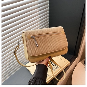 Close-up of a cream crossbody bag featuring woven texture flap and metallic zipper detail