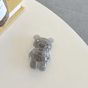 Macro detail of bear-shaped phone grip in translucent grey resin with gold foil flakes