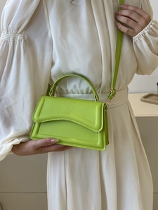 Close-up of vibrant neon green leather handbag featuring a curved handle and flap closure