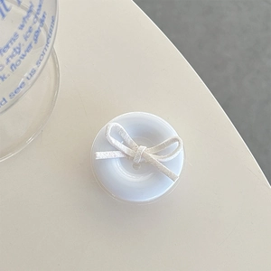 Macro shot of white matte circular phone grip featuring a minimalist decorative cream bow