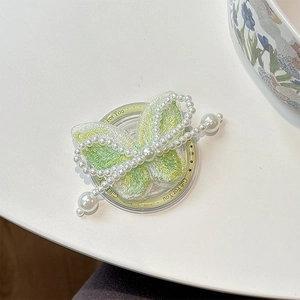 Detailed macro of embroidered green butterfly phone grip with white pearl accents
