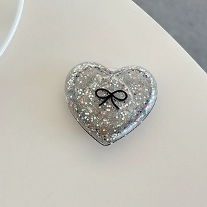 Detail of silver heart phone grip featuring glitter finish and black bow design